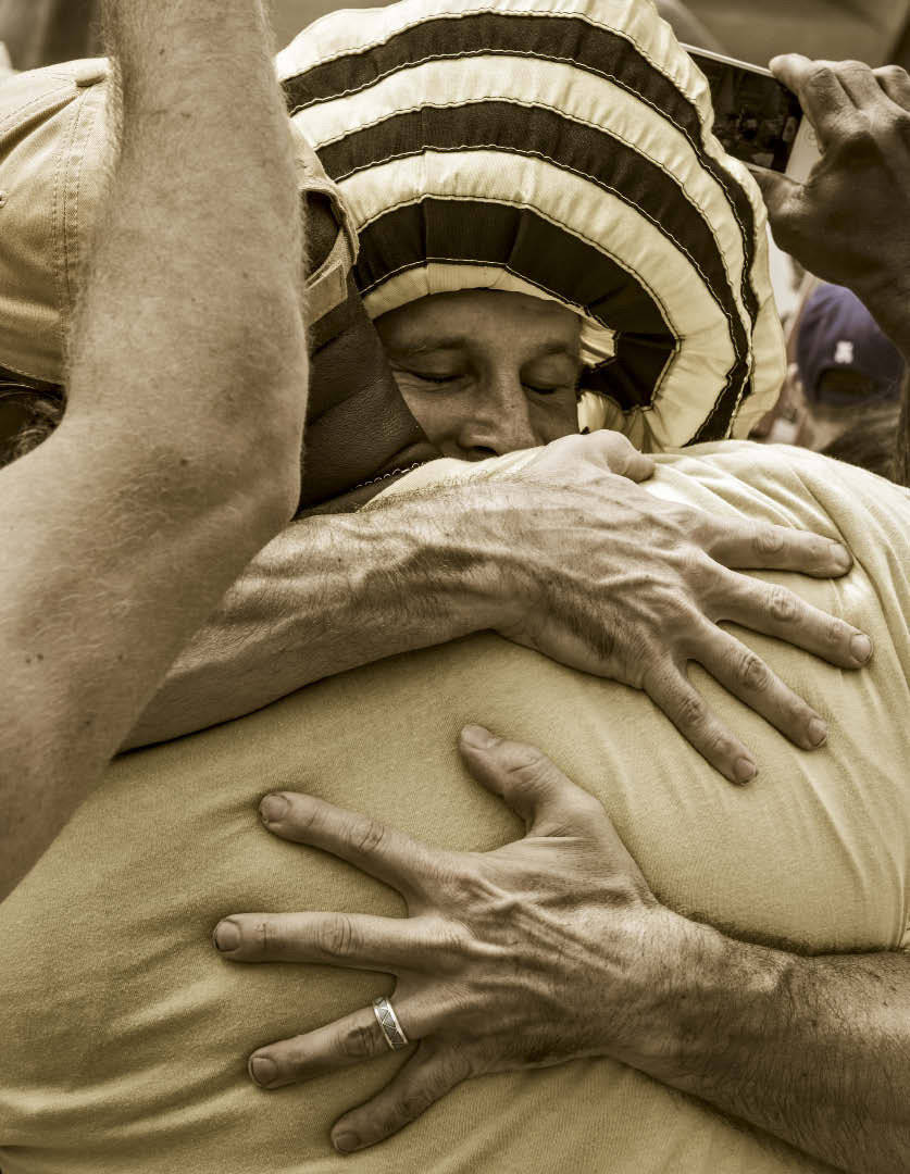SWEET GREET At a recent protest, Brandon Pollard embraces a man in the crowd. The beekeeper and environmentalist is known around the neighborhood for his hugs. He gives big burly hugs, generously, often with his eyes closed. Photo by Danny Fulgencio