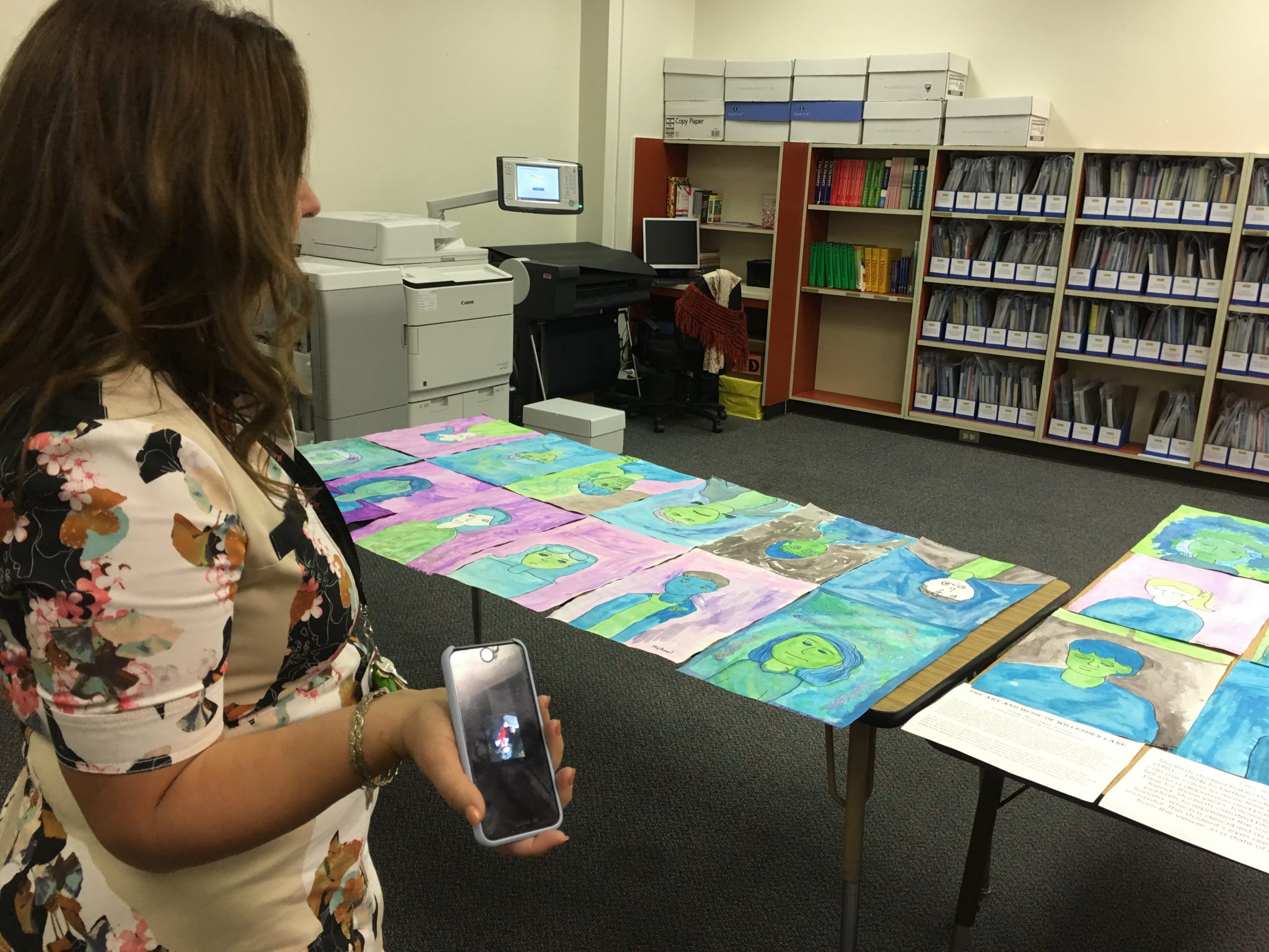 Music teacher Natalie Herbert plays classical music from her phone to help explain the artwork her students made. 