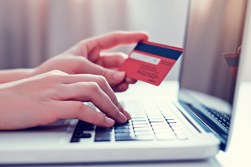 Hands holding credit card and using laptop. Online shopping. Getty Image