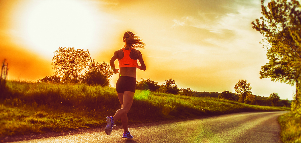 Photo of a female jogger in the countryside, with sun flare in the background.