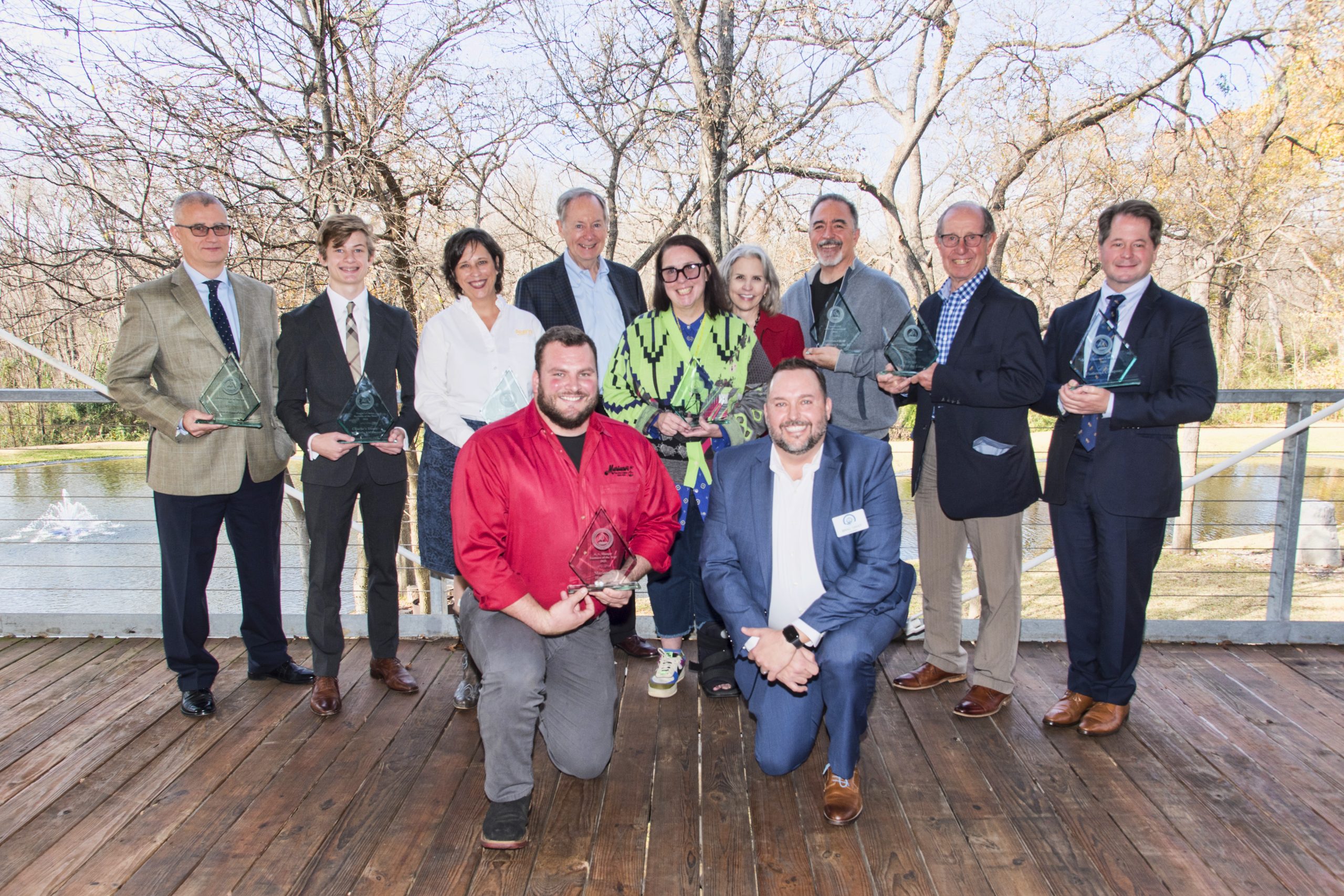 Recipients of the Business of the Year Awards pose in front of a pond.