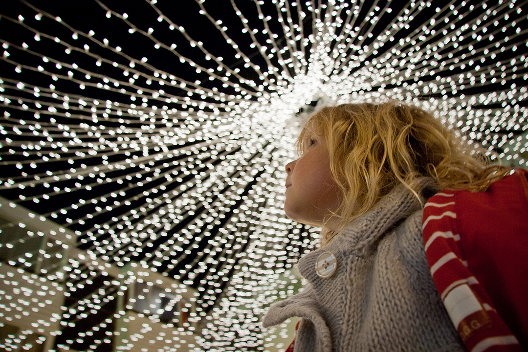 Girl looking upwards at fairy lights