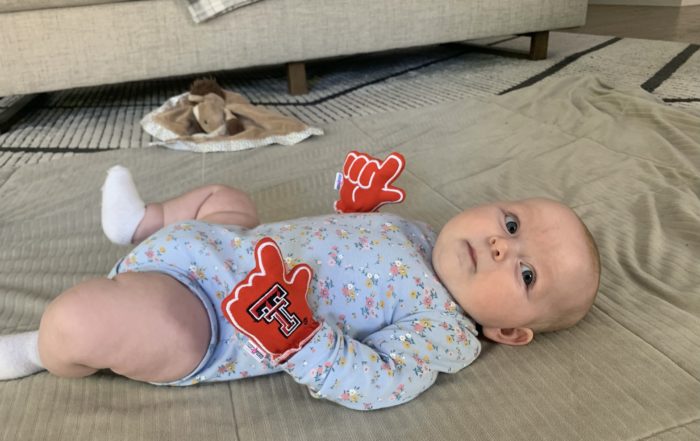 Baby wears Texas Tech mittens
