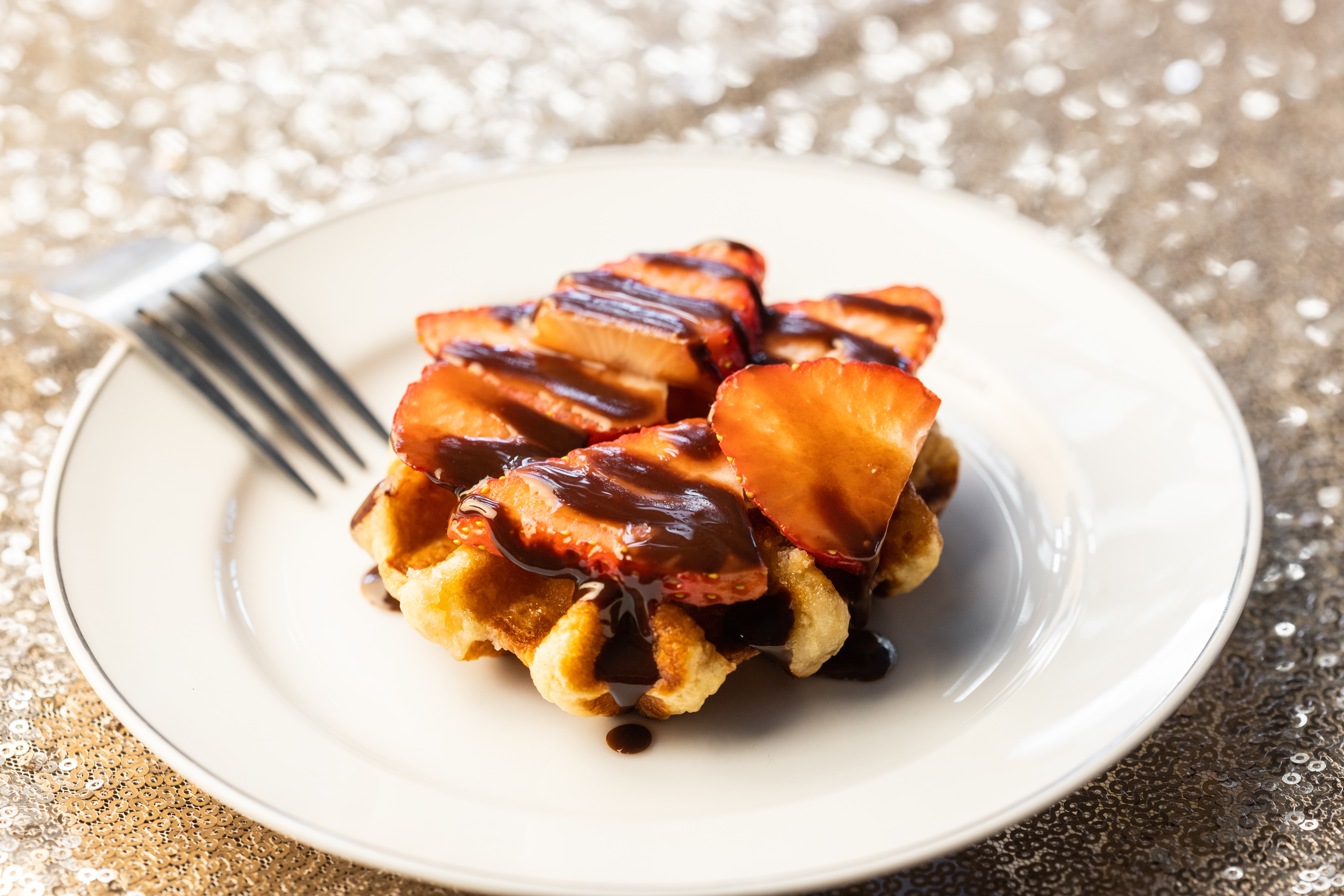 The Liege waffle, a traditional Belgian waffle, is made with pearl sugar and served with a choice of toppings, such as strawberries and Dutch chocolate sauce.