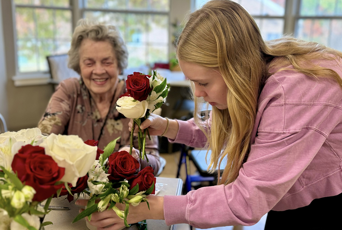 Juliette Fowler staff member demonstrates flower arranging for a resident before residents make their own arrangement. Photo courtesy of Juliette Fowler.