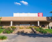 A building with a concrete awning. It says "Rosewood Center for the Family Arts" and above that, "Dallas Children's Theater." The property is landscaped with grass, shrubs and trees.