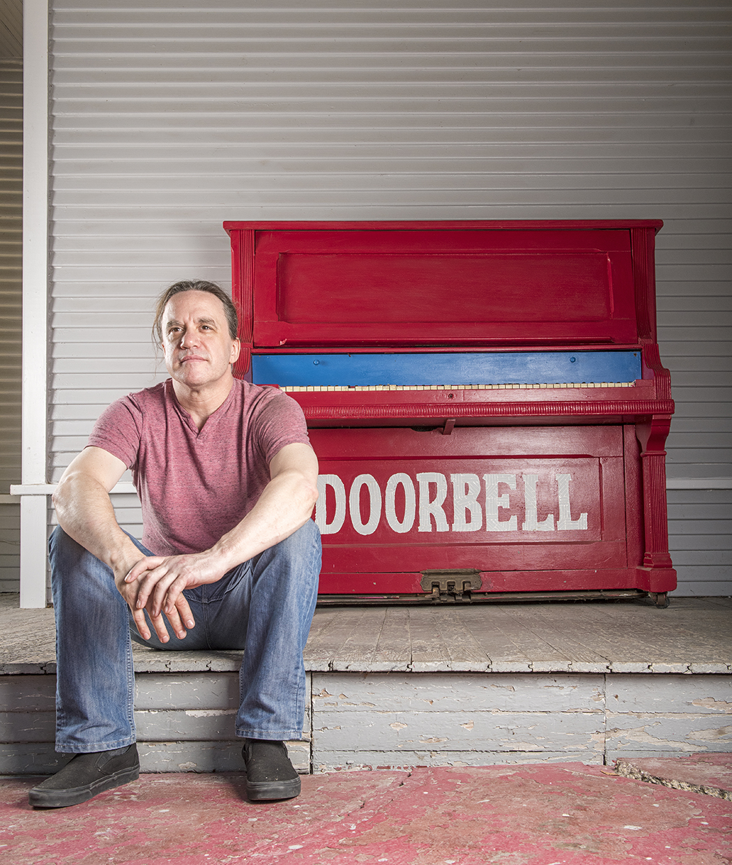 Man in front of piano painted with "doorbell" on it.